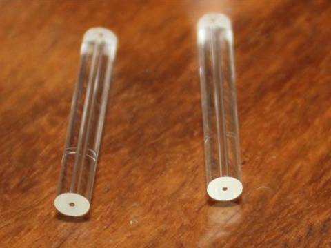 Two round micro capillary tubes with a cavity inserted in each on a even surface.