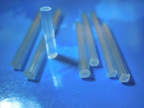 Seven round micro capillary tubes with seven cavities inserted in each on blue background.