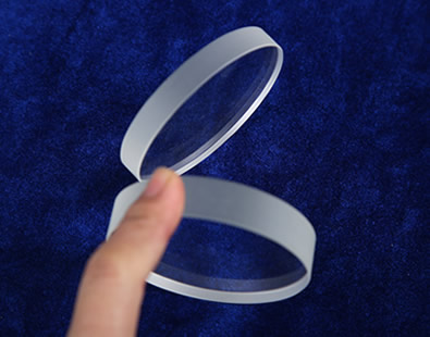 Two pieces of glass discs stands on the desk and the edge is smooth and polished.