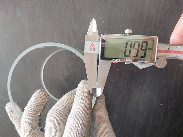 A worker is measuring the precision glass cylinder chamfer depth.
