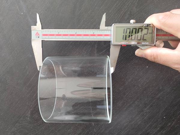 A worker is measuring the precision glass cylinder height.